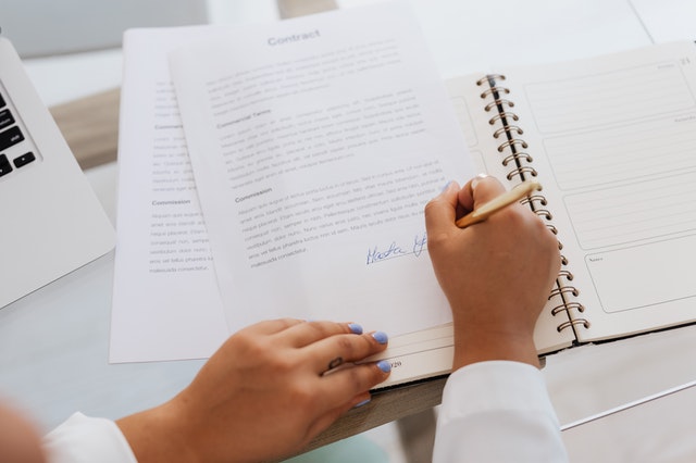 person signing a lease agreement using a blue pen